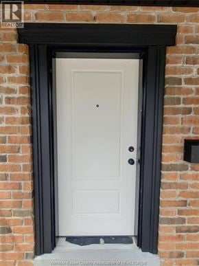 Windsor triplex for rent - A white door with a black frame is set in a brick wall.