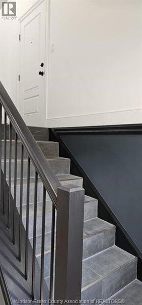 Windsor triplex for rent - A staircase with a black railing and white steps.