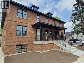 Windsor triplex for rent - A red brick house with a black metal railing on the porch.
