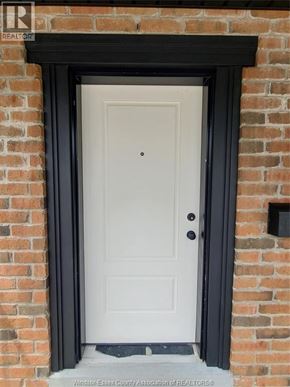 Windsor triplex for rent - A white door with a black frame is set in a brick wall.