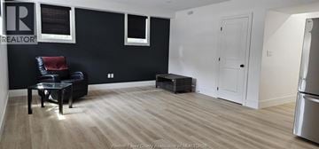 Windsor house for rent - A black and white living room with a black leather chair and a wooden floor.