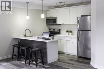 Windsor triplex for rent - A kitchen with a bar stool and a laptop on the counter.