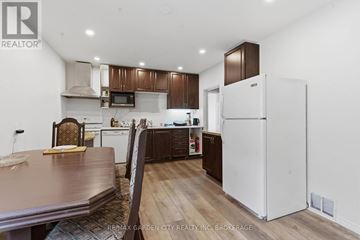 St. Catharines (Western Hill) multi-family for rent - A kitchen with a white refrigerator and brown cabinets.