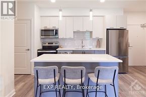 Ottawa condo for rent - A kitchen with white cabinets and a white island with two chairs.