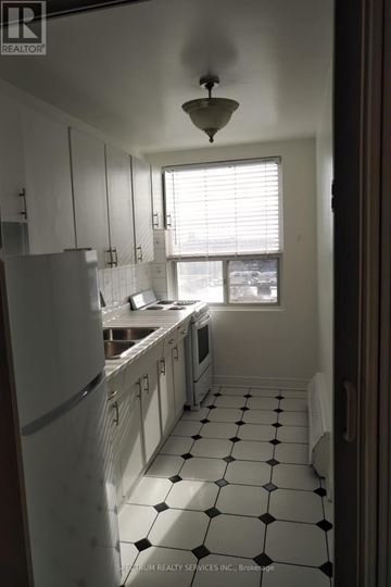Toronto (Yorkdale-Glen Park) condo for rent - A kitchen with white cabinets and black and white tiles.