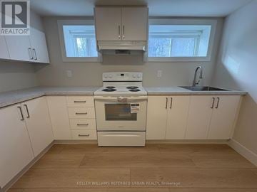 Toronto (Clanton Park) house for rent - A kitchen with white cabinets and a stove top oven.
