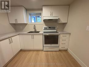 Toronto (Clanton Park) house for rent - A kitchen with white cabinets and a stove top oven.