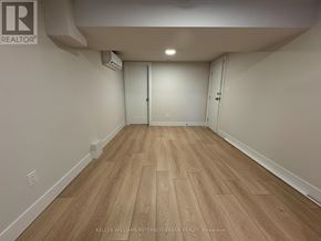 Toronto (Clanton Park) house for rent - A spacious room with wooden flooring and white walls.