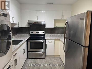 Toronto (Greenwood-Coxwell) house for rent - A kitchen with white cabinets and a black stove top oven.