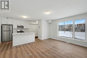 Ottawa townhouse for rent - A spacious, empty room with a kitchenette and a view of a snowy landscape outside.