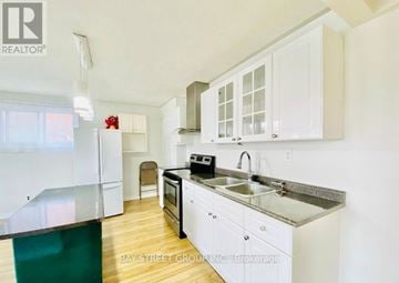 Oshawa (Vanier) house for rent - A kitchen with white cabinets and a black stove top oven.