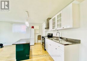 Oshawa (Vanier) house for rent - A kitchen with white cabinets and a green island.