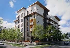 Calgary apartment for rent - A modern multi-story apartment building with balconies and trees in front.