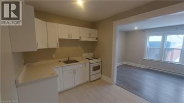 Kitchener apartment for rent - A kitchen with white cabinets and a window.