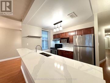 London East (East F) condo for rent - A kitchen with a white counter top and a stainless steel refrigerator.