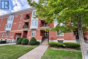 London East (East F) condo for rent - A red brick apartment building with green bushes and trees in front.