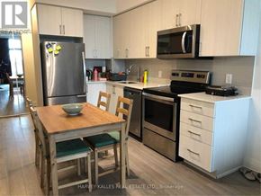 Toronto (Bayview Village) condo for rent - A kitchen with a wooden table and chairs, a refrigerator, a microwave, and a stove top oven.