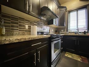 Surrey house for rent - A kitchen with black cabinets and a granite countertop.