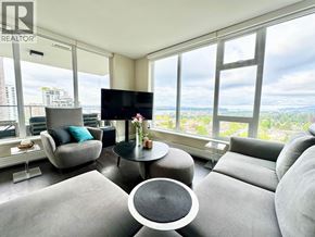 Vancouver apartment for rent - A living room with a grey sofa, a black TV and a glass table with a vase of flowers on it.