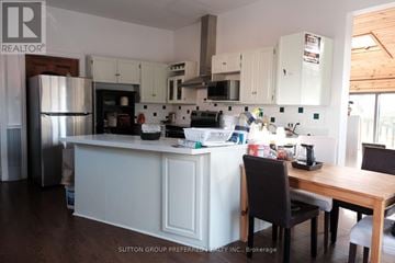 London East (East B) house for rent - A kitchen with white cabinets and a wooden table.