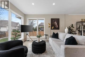 Richmond Hill (South Richvale) house for rent - A living room with a grey couch, a black chair, and a black lamp on a tripod stand.