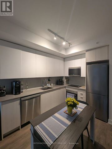Oakville (Ro River Oaks) condo for rent - A kitchen with a wooden table and a vase of flowers on it.