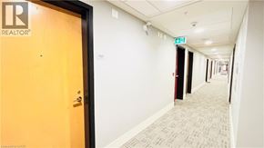 Kitchener condo for rent - A hallway with a door on the left and a green exit sign above the door.