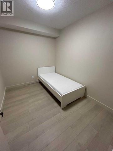 For rent in Calgary - A bedroom with a bed and a wooden floor.