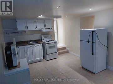 Toronto (Weston) triplex for rent - A kitchen with a refrigerator, stove, and cabinets.