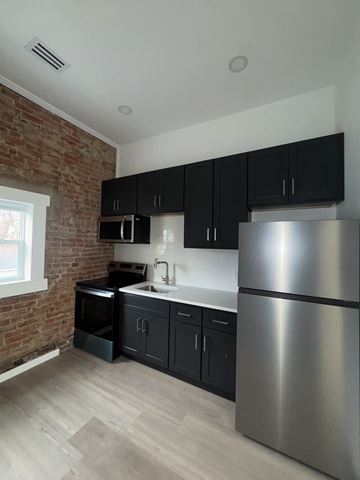 Louisville apartment for rent - A kitchen with a stainless steel refrigerator and black cabinets.