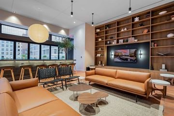 Cincinnati apartment for rent - A modern living room with a large orange sofa and a wooden shelf with various objects on it.