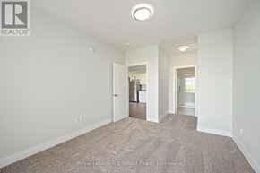 Tillsonburg multi-family for rent - A large, empty room with a carpeted floor and white walls.