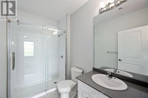 Tillsonburg multi-family for rent - A white toilet sits in a bathroom next to a sink and a walk-in shower.