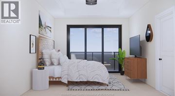 Windsor condo for rent - A bedroom with a large bed and a window overlooking the water.