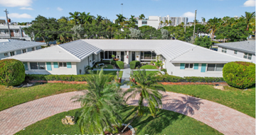 Fort Lauderdale apartment for rent - A white building with a grey roof surrounded by greenery and a brick pathway.