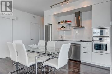 Toronto (Waterfront Communities) condo for rent - A modern kitchen with white chairs and stainless steel appliances.