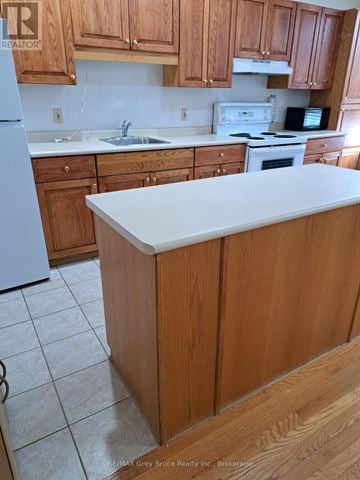 Meaford condo for rent - A kitchen with wooden cabinets and a white island.