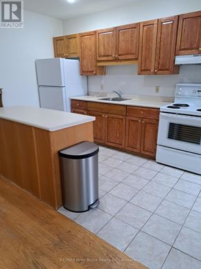 Meaford condo for rent - A kitchen with wooden cabinets and white appliances.