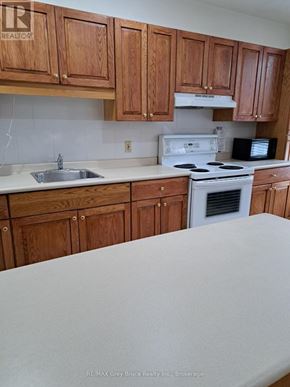 Meaford condo for rent - A kitchen with wooden cabinets and white appliances.