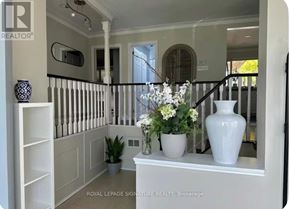Oakville (Wo West) house for rent - A white vase with flowers sits on a white console table in a room with white walls and a black railing.
