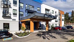 Brantford apartment for rent - A modern multi-story building with a parking lot in front.