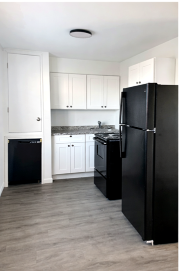 Baton Rouge apartment for rent - A black refrigerator stands in a kitchen with white cabinets.