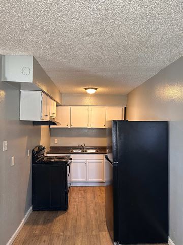 Baton Rouge apartment for rent - A black refrigerator stands in a kitchen with white cabinets and a black dishwasher.