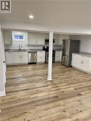 Hamilton house for rent - A kitchen with wooden floors and white cabinets.