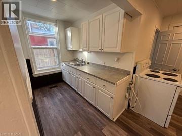 Brantford house for rent - A kitchen with white cabinets and a stove top oven.