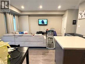 Welland townhouse for rent - A living room with a grey sofa and a television on the wall.