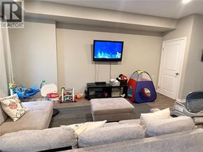 Welland townhouse for rent - A living room with a grey couch, a television, a gaming console, and a bean bag chair.