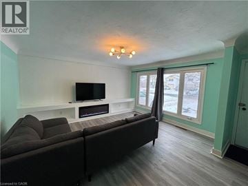 St. Catharines house for rent - A living room with a grey couch and a television on a white stand.