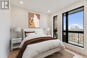 Lincoln (Beamsville) multi-family for rent - A bedroom with a large bed, a nightstand, and a window overlooking a brick building.