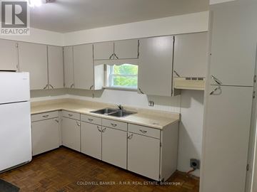Cobourg duplex for rent - A kitchen with white cabinets and a white fridge.